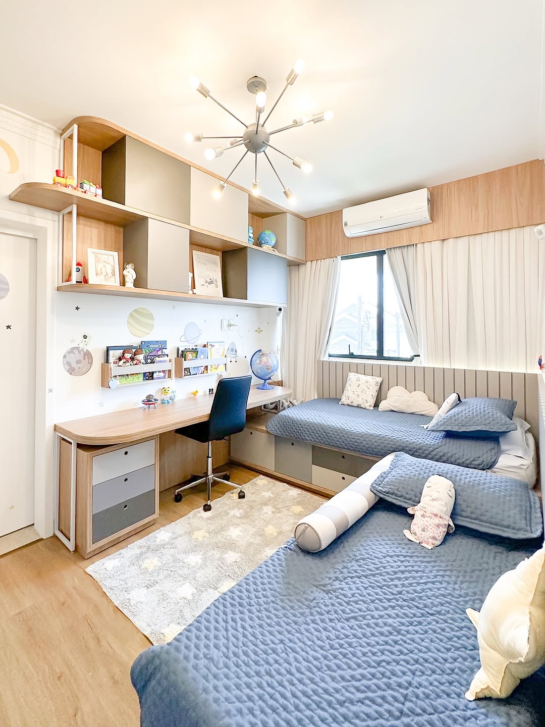 Quarto infantil com tema de astronauta, duas camas, bancada de estudos e marcenaria em madeira e azul.