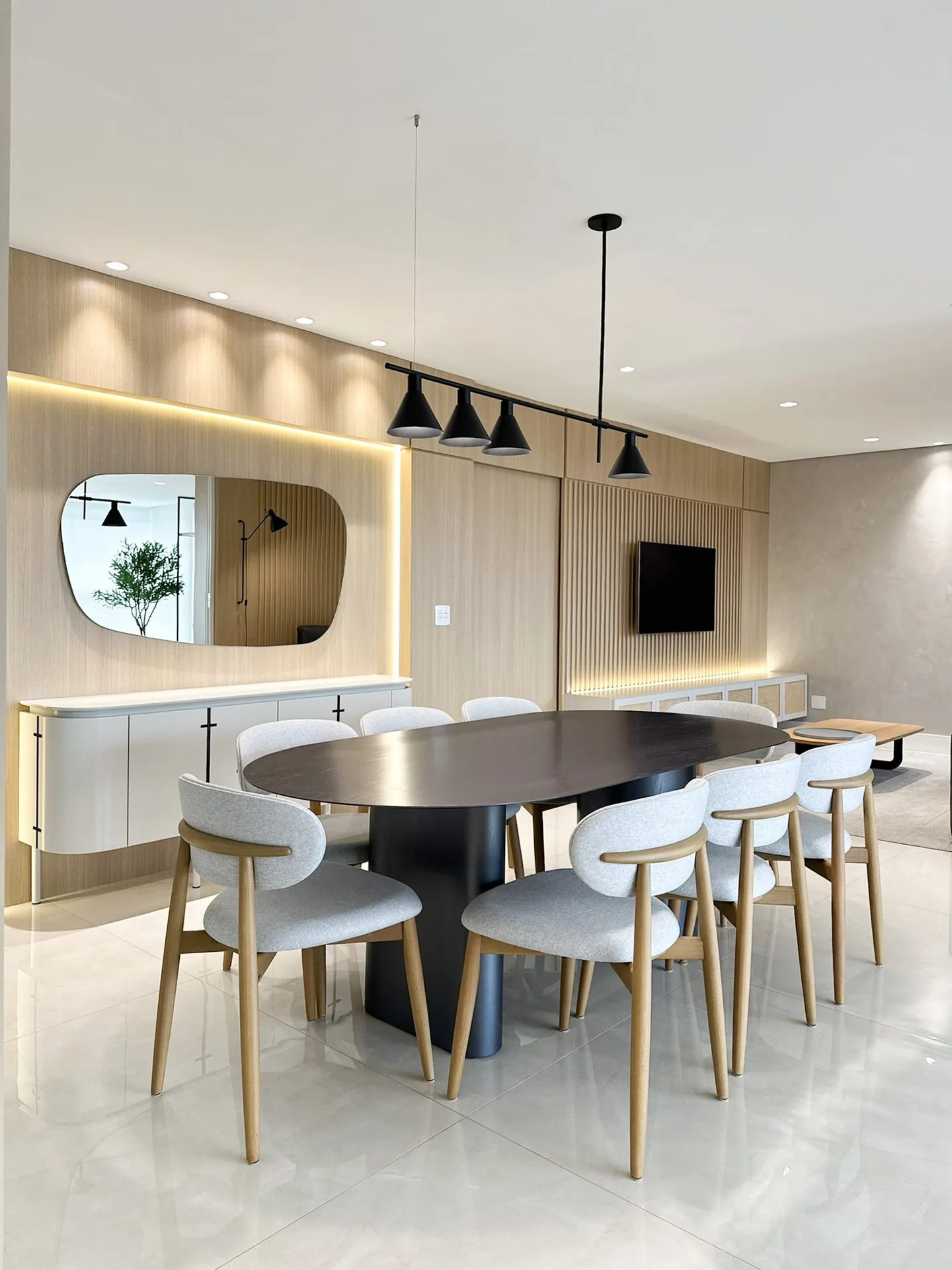 Projeto de interiores de apartamento executado, com marcenaria clara sob medida, sala de jantar com painel iluminado e ambientes de linhas calmas.