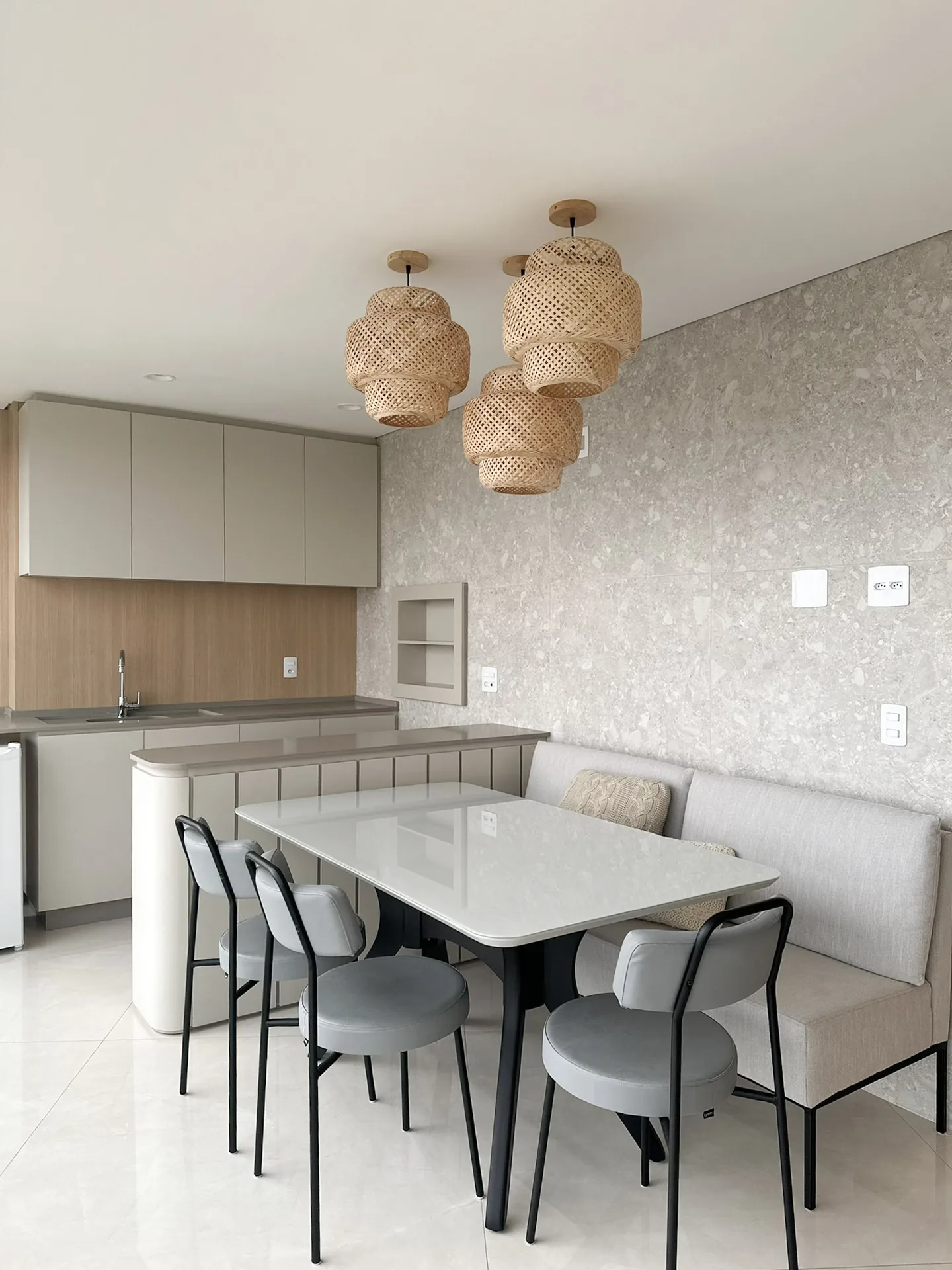 Cozinha integrada à mesa de jantar, com pendentes de fibra natural e banco estofado