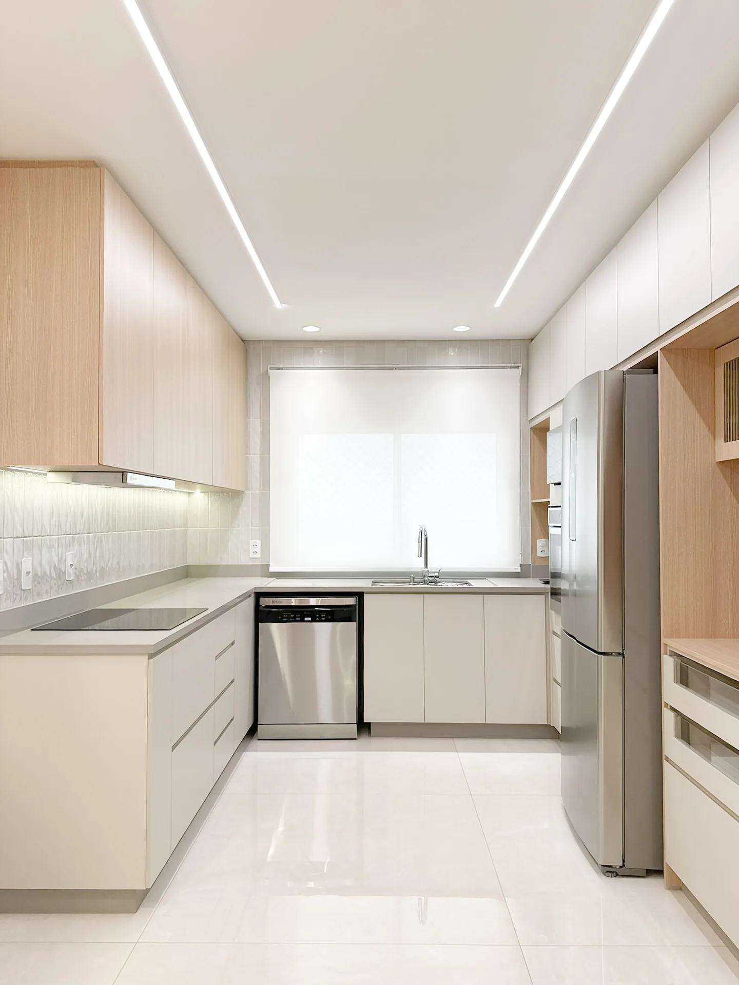 Cozinha em U com marcenaria clara, bancada de pedra e iluminação linear